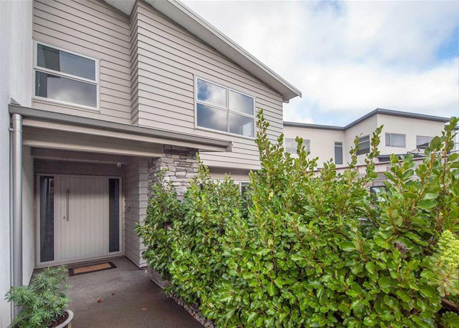 Modern two-story house with light gray siding and entry porch.