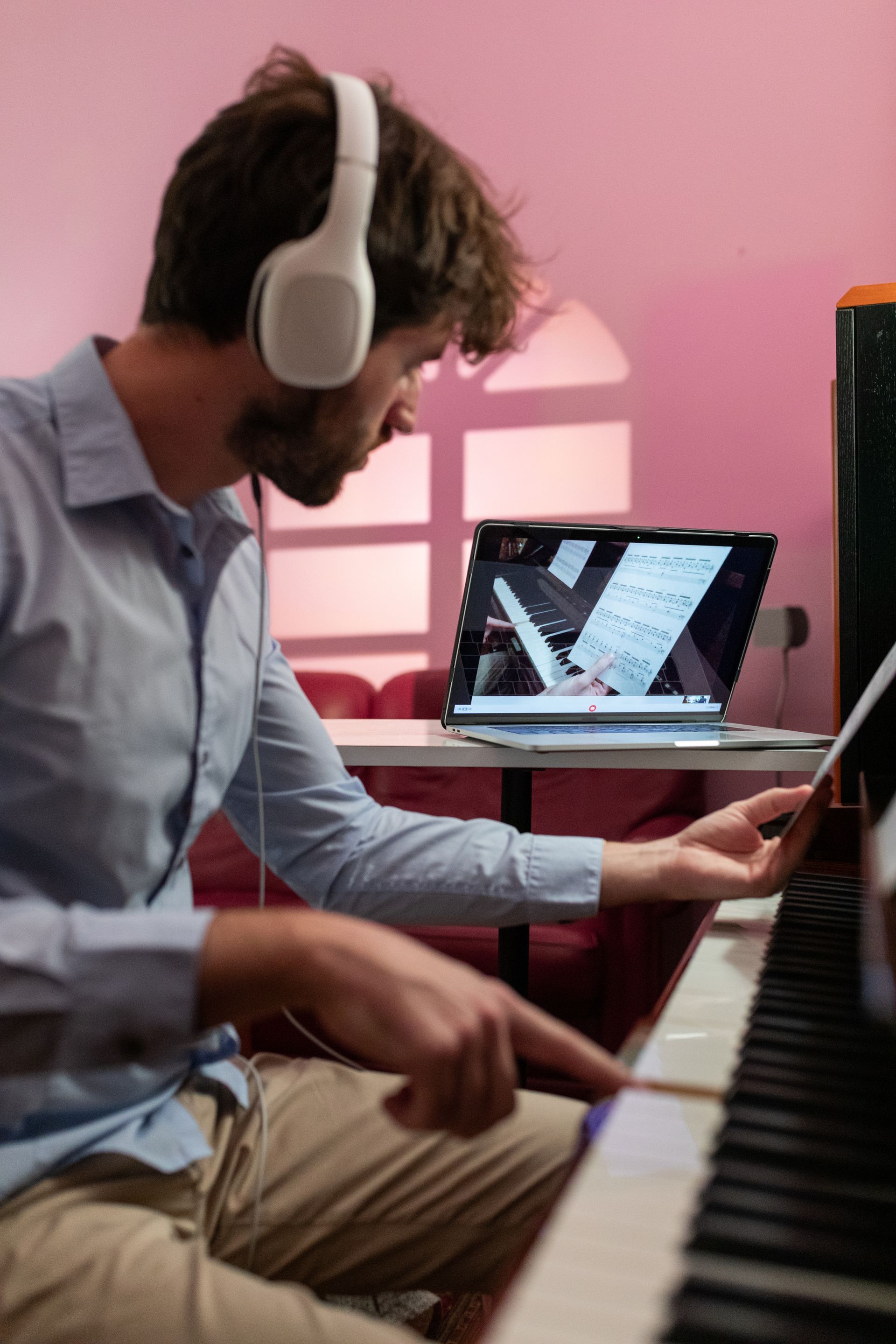 A man wearing headphones is playing a piano