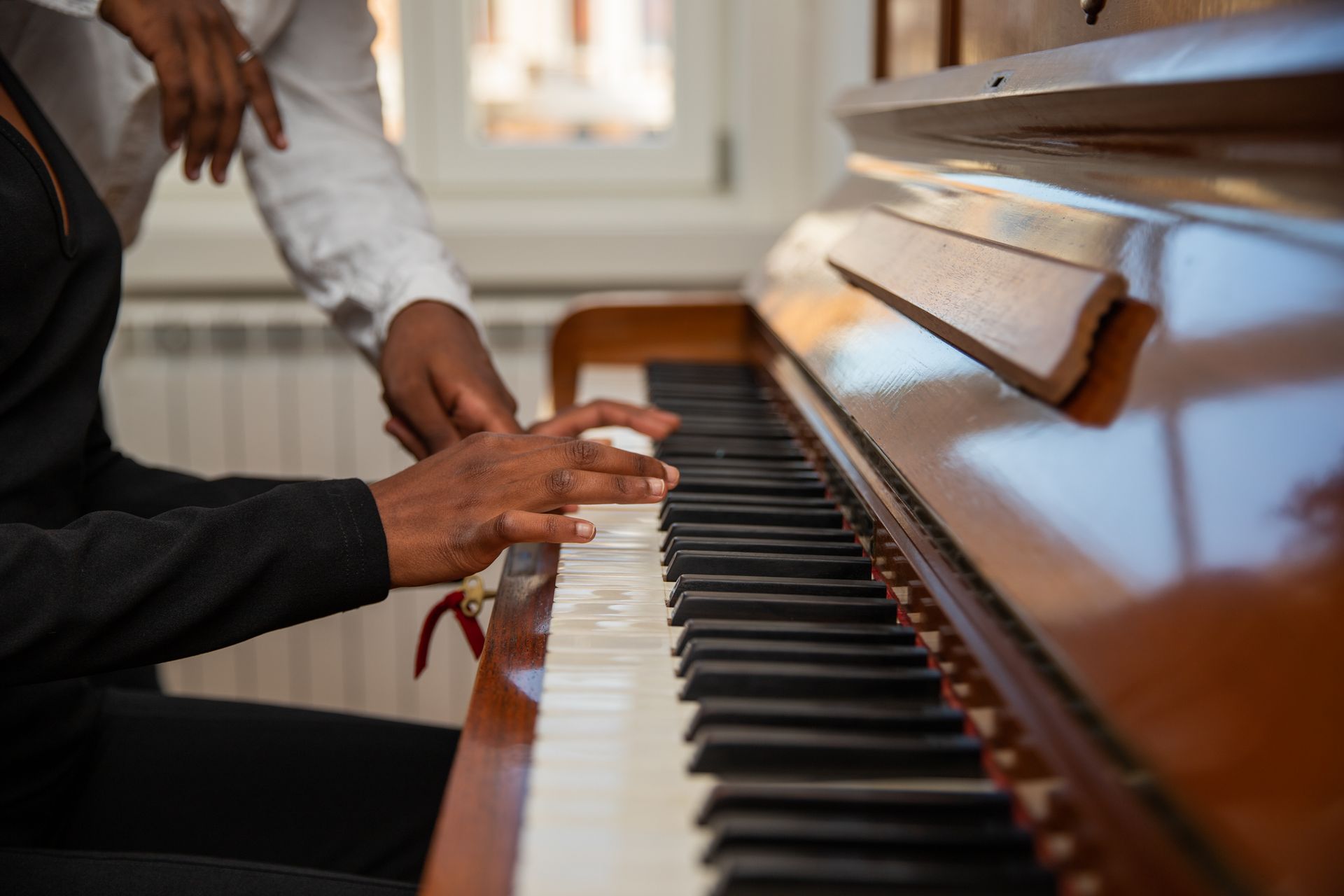 A man is teaching a woman how to play the piano.