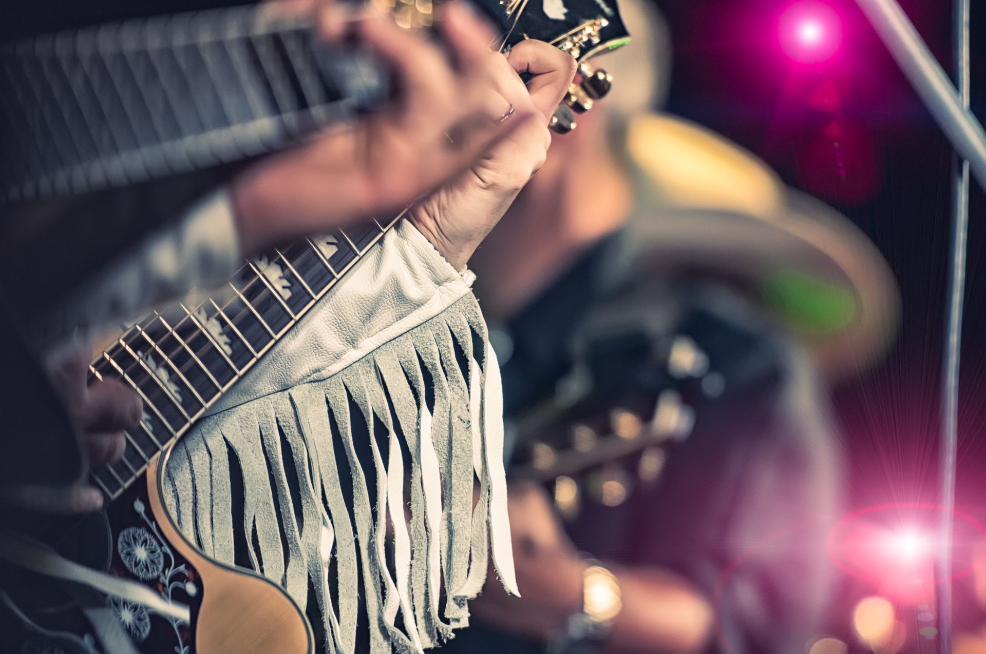 A close up of a person playing a guitar on a stage.