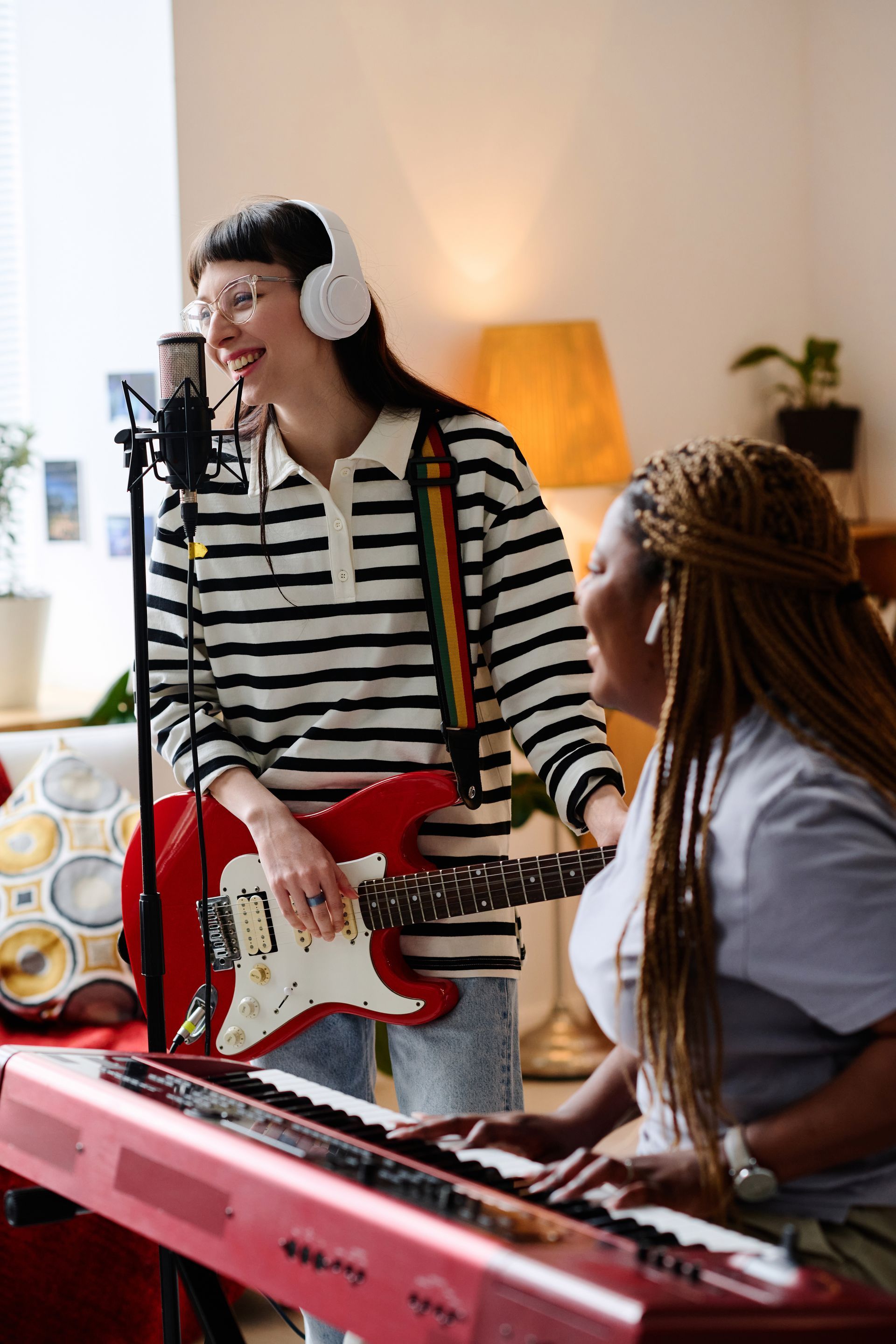 A woman is playing a guitar and another woman is playing a keyboard.