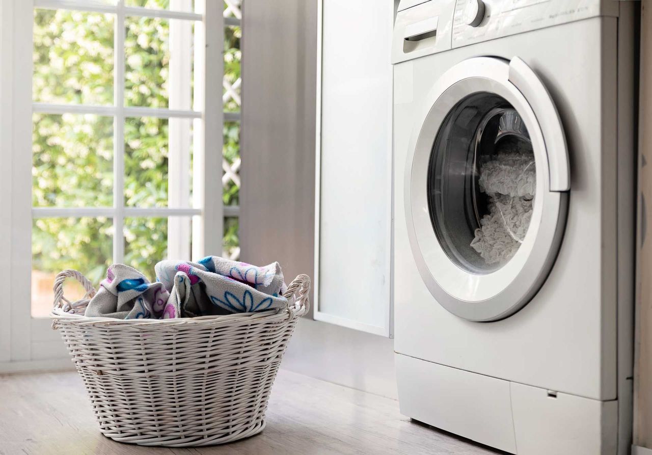 A laundry room with a washing machine and a basket of clothes.