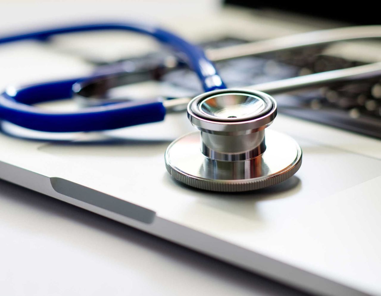 A stethoscope is sitting on top of a laptop computer.