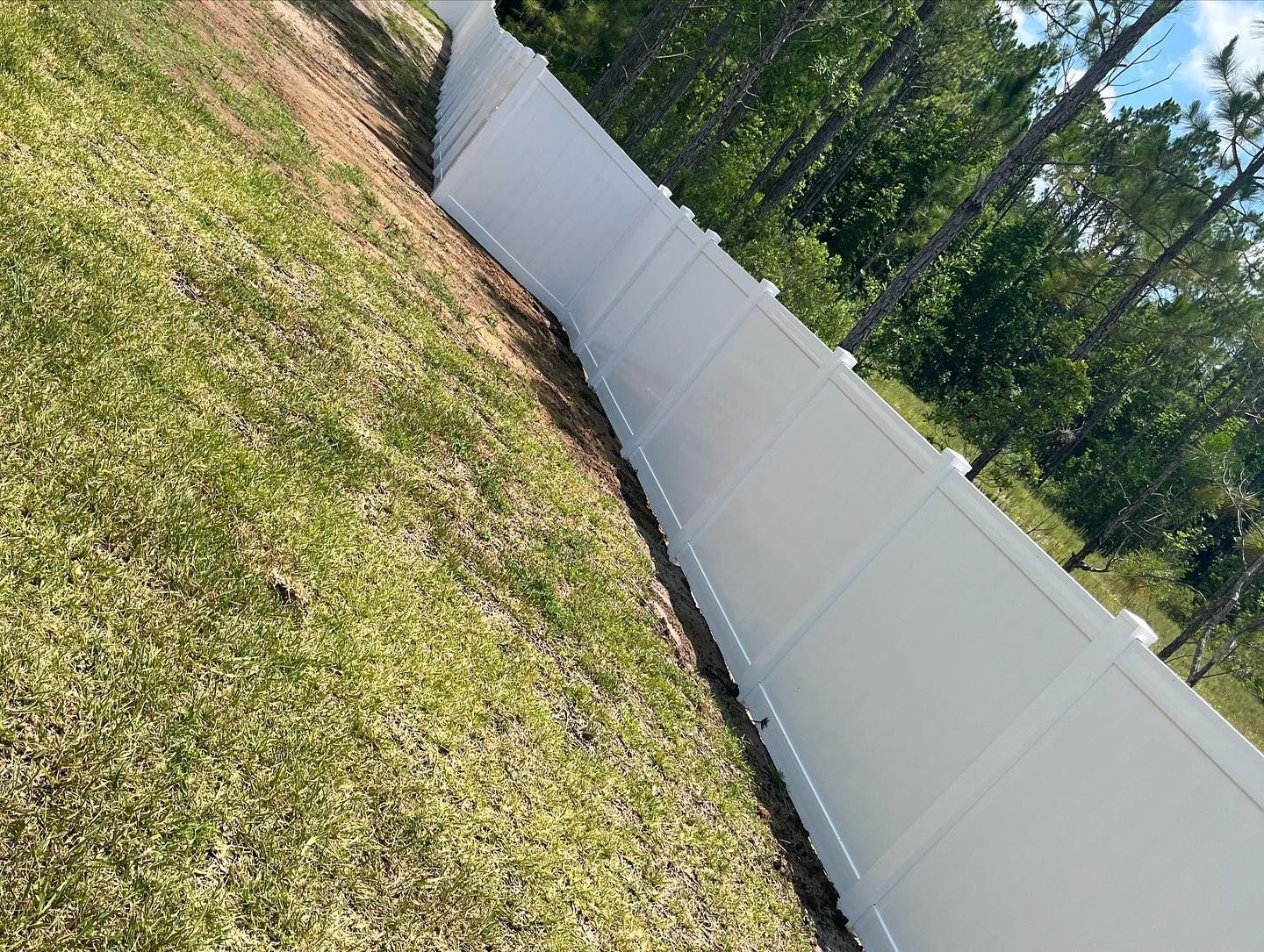 A white fence is sitting on top of a grassy hill.
