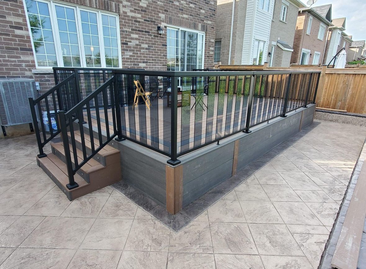 A patio with a railing and stairs in front of a house.