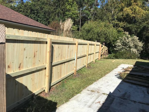 A wooden fence is being built in the backyard of a house.