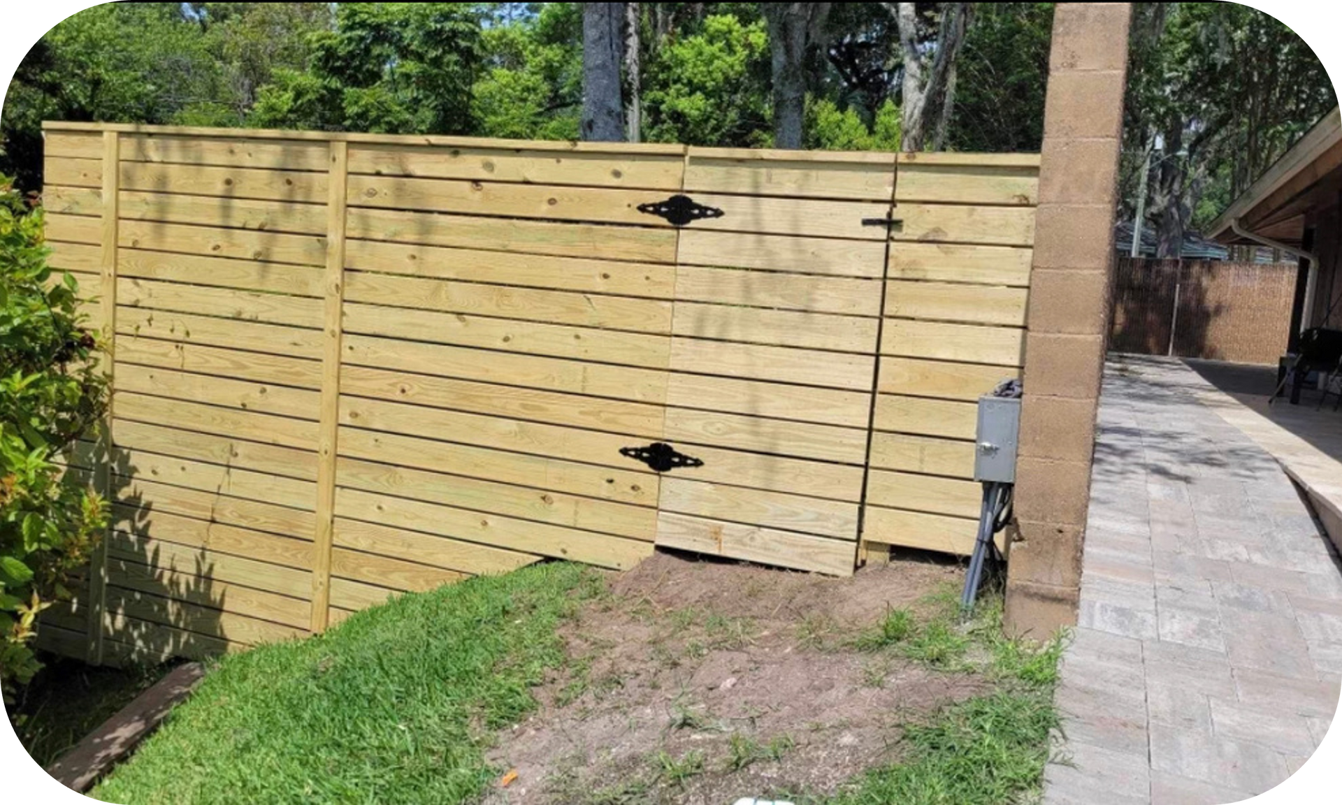 A wooden fence with a gate in the backyard of a house.
