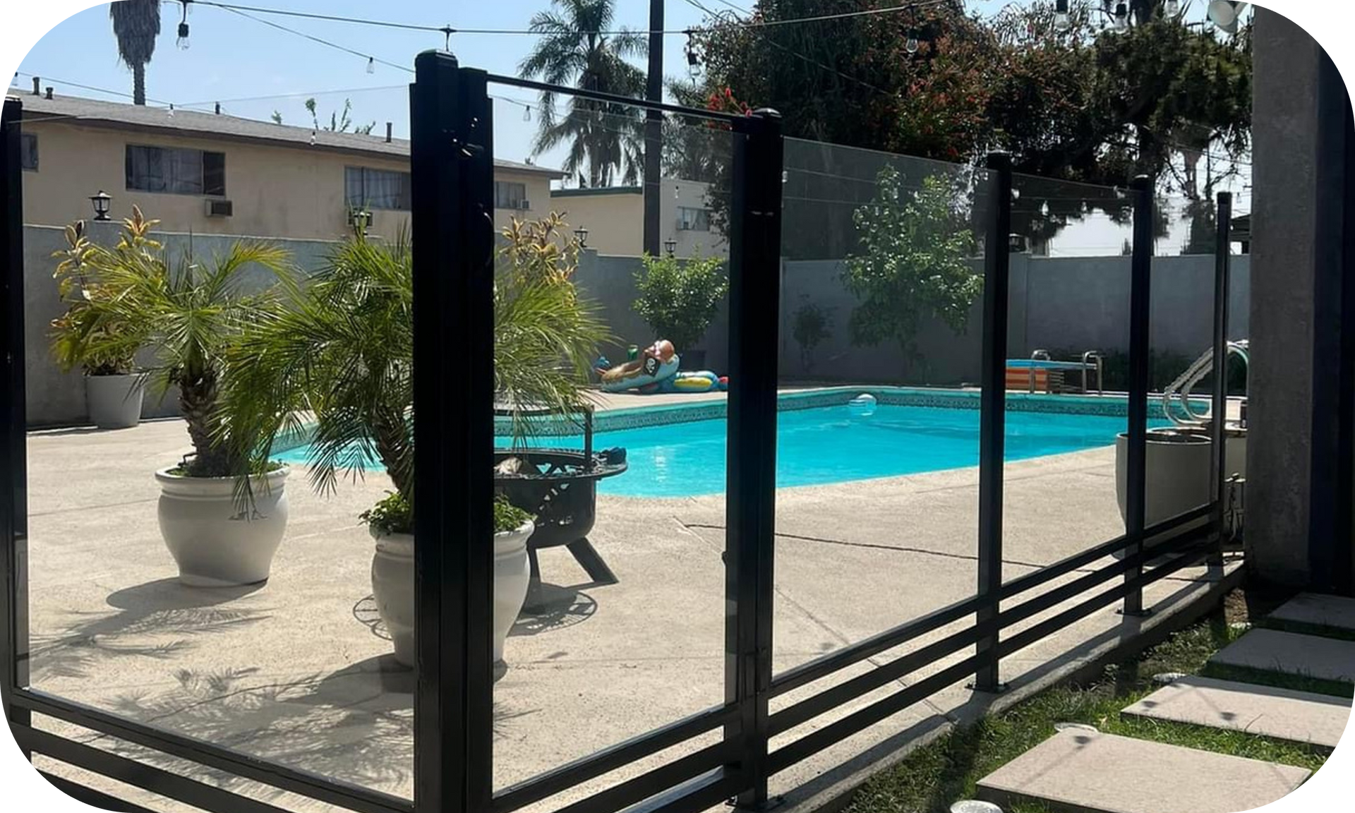 A fence surrounds a swimming pool in a backyard