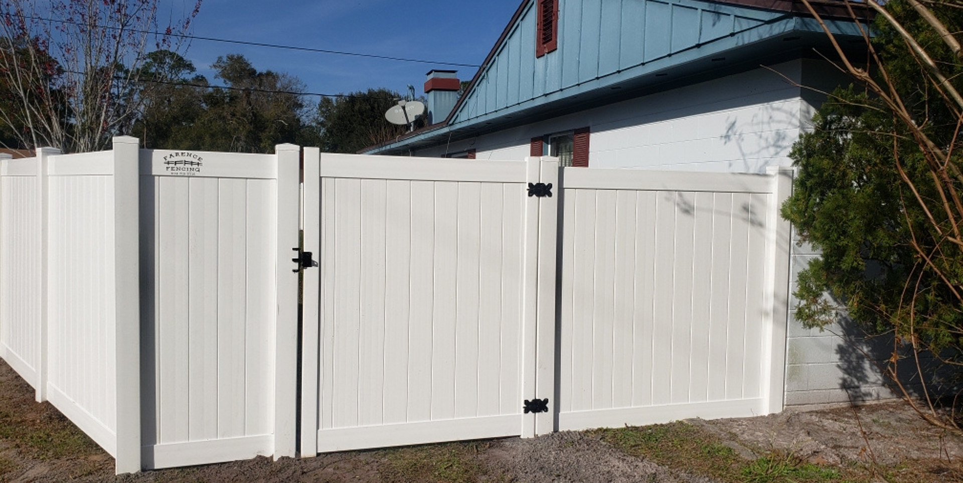 A white fence with a gate is in front of a house.