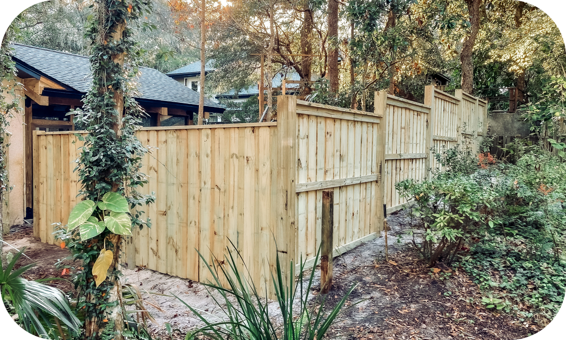 A wooden fence surrounds a house in the woods.