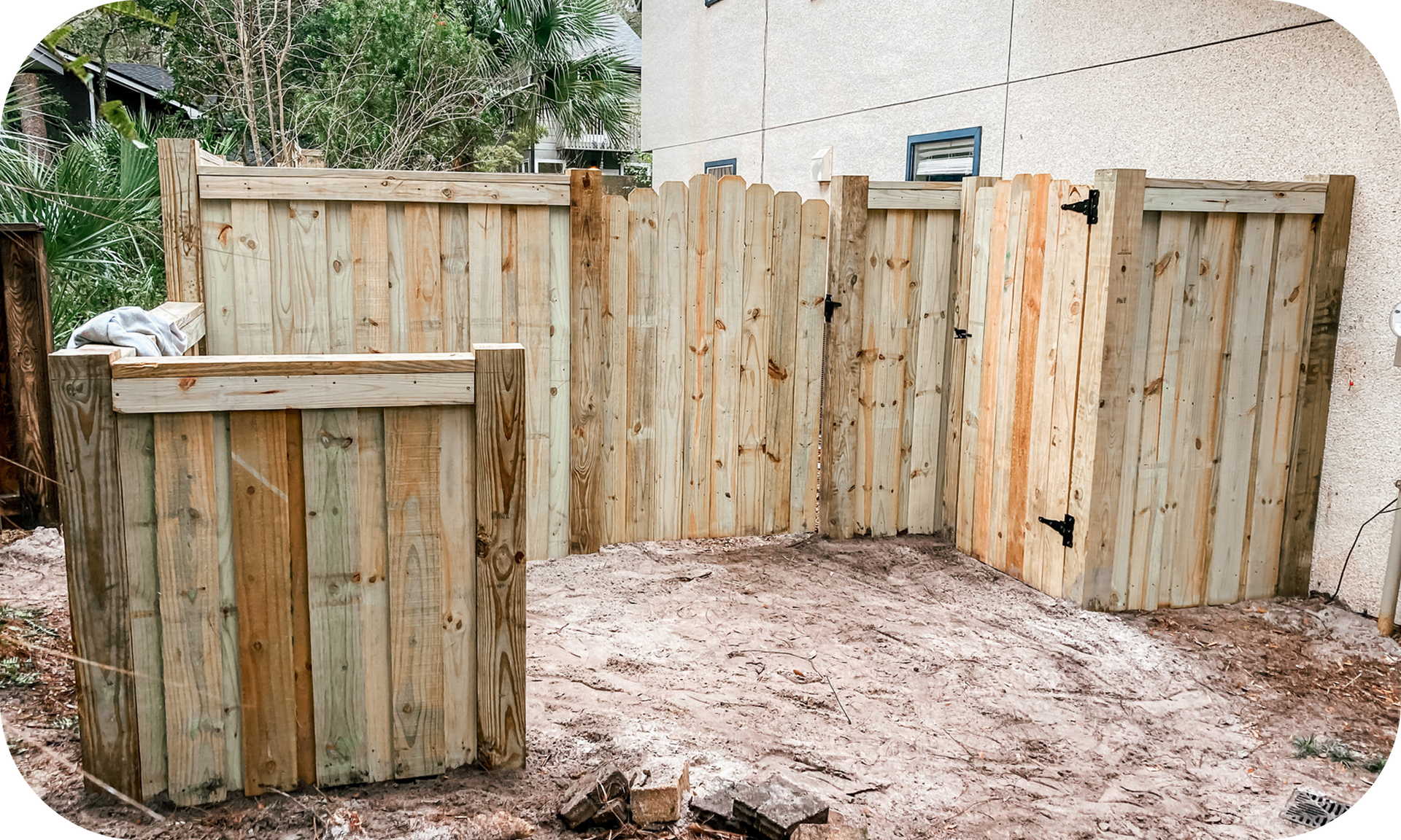 A wooden fence is sitting in the dirt in front of a building.