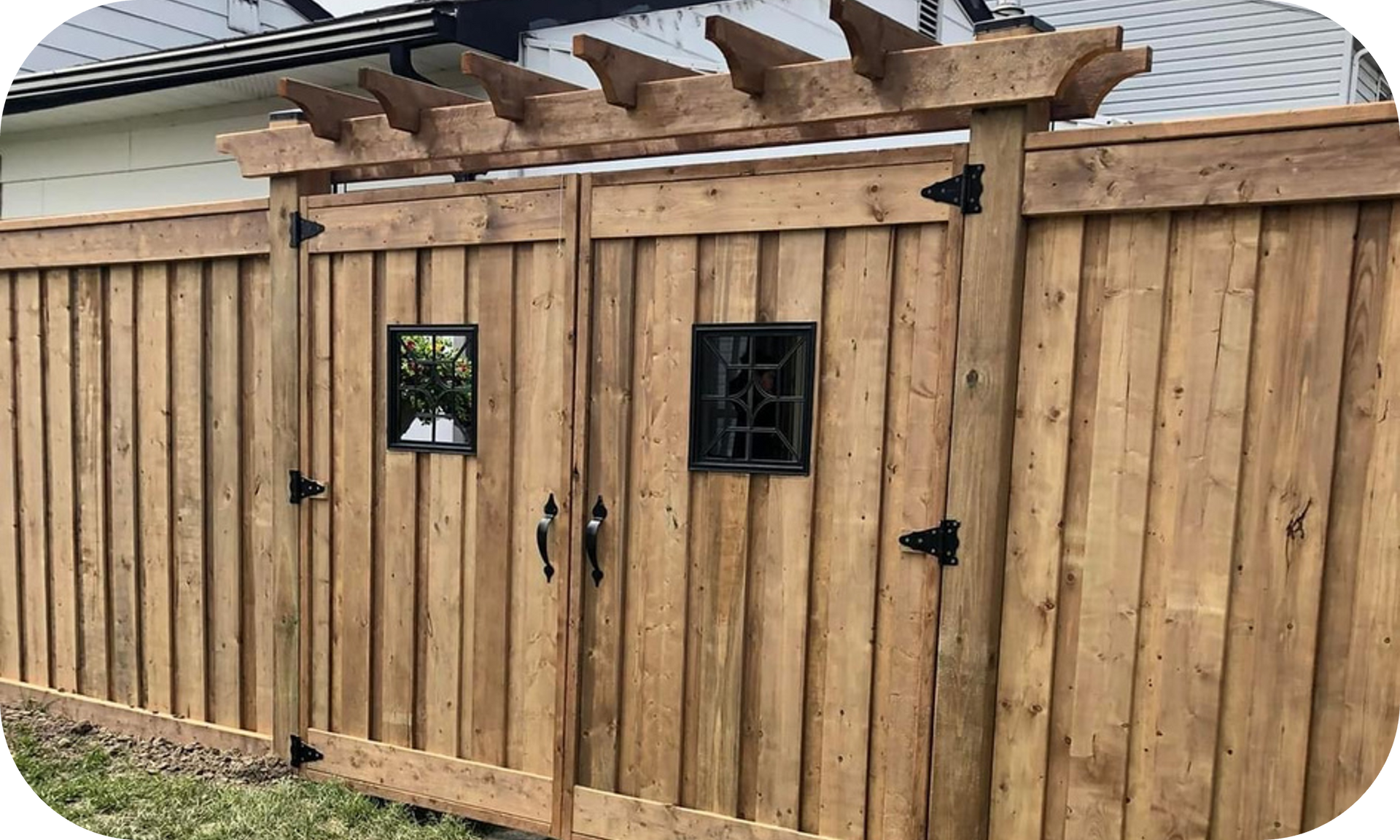 A wooden fence with a pergola and a gate in front of a house.