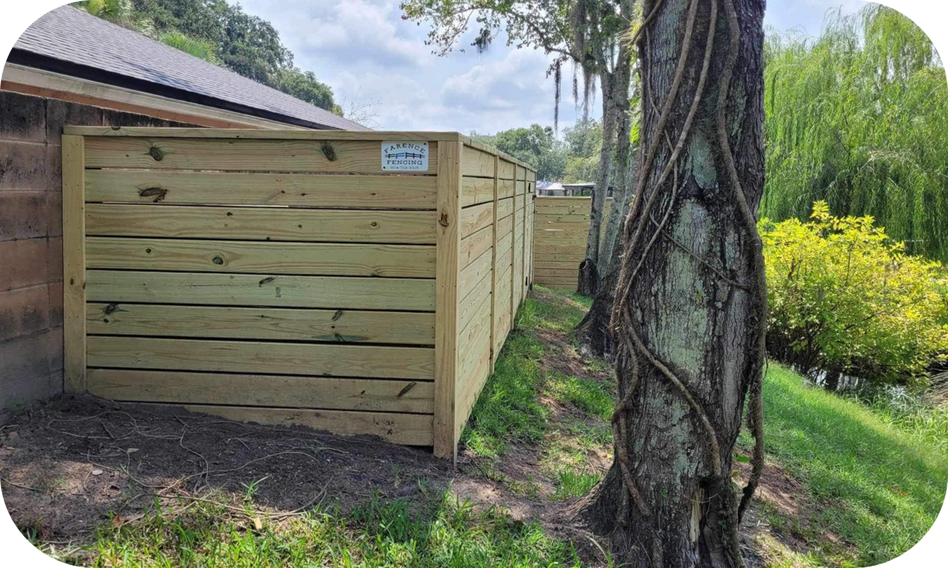 A wooden fence is sitting next to a tree in a yard.