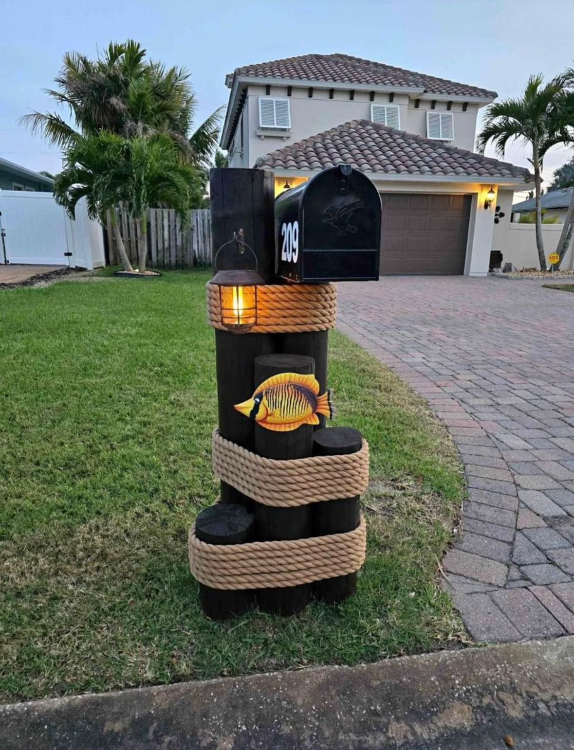 A mailbox is wrapped in rope in front of a house.