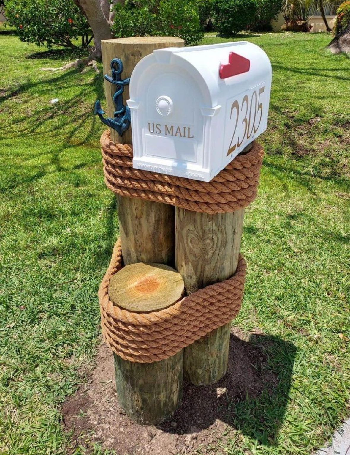 A white mailbox is tied to a wooden post with rope.