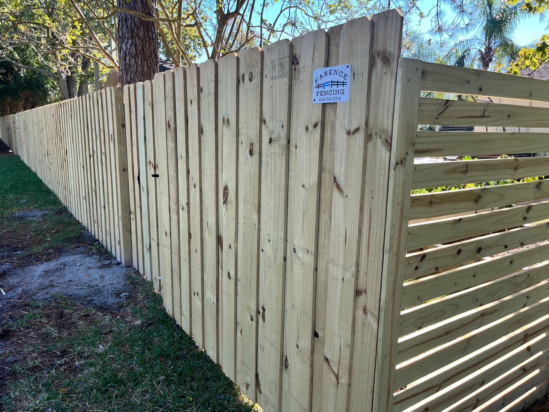 A long wooden fence is sitting on top of a lush green field.