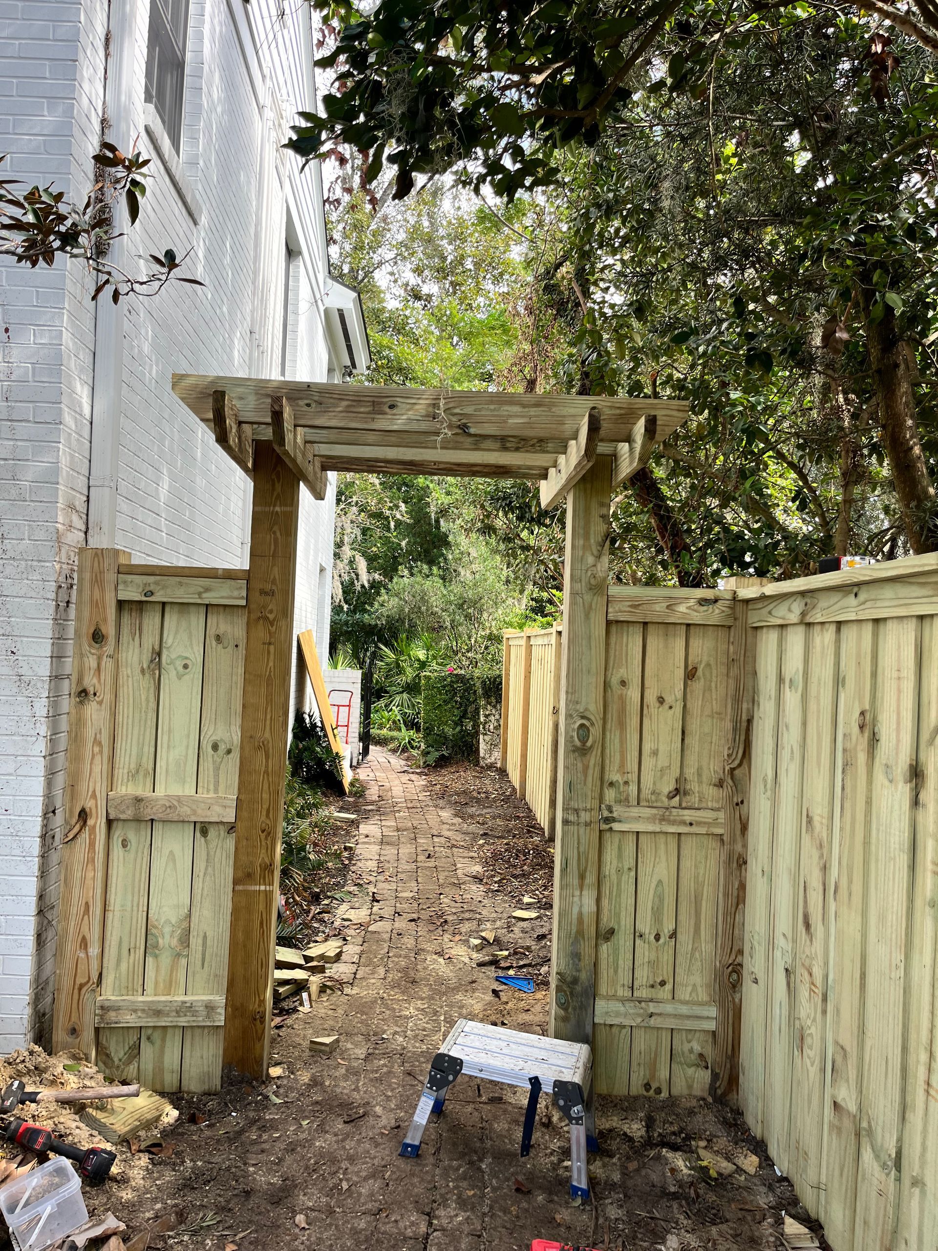 A wooden pergola is being built next to a wooden fence.