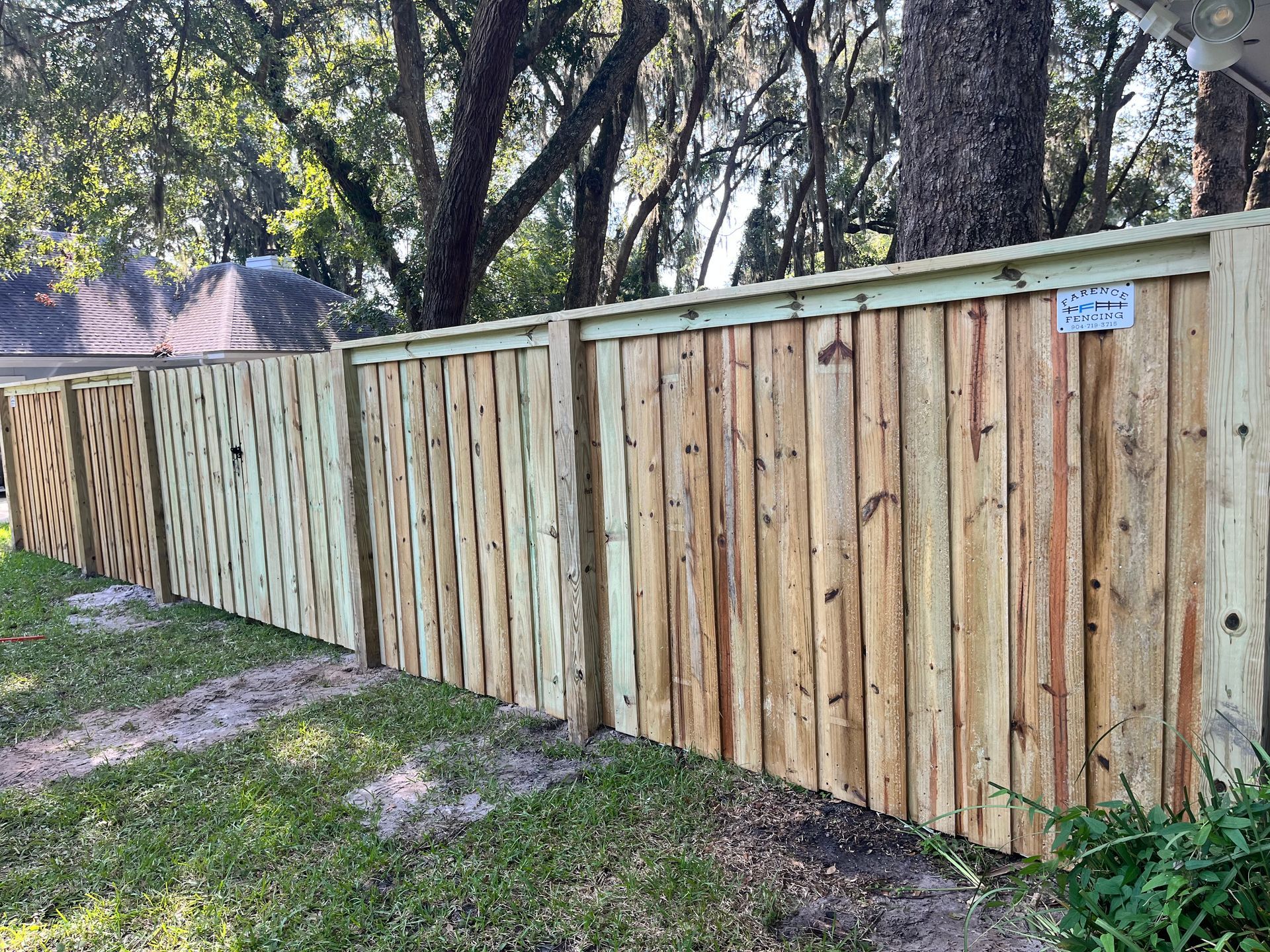 A wooden fence is surrounded by trees in a yard.