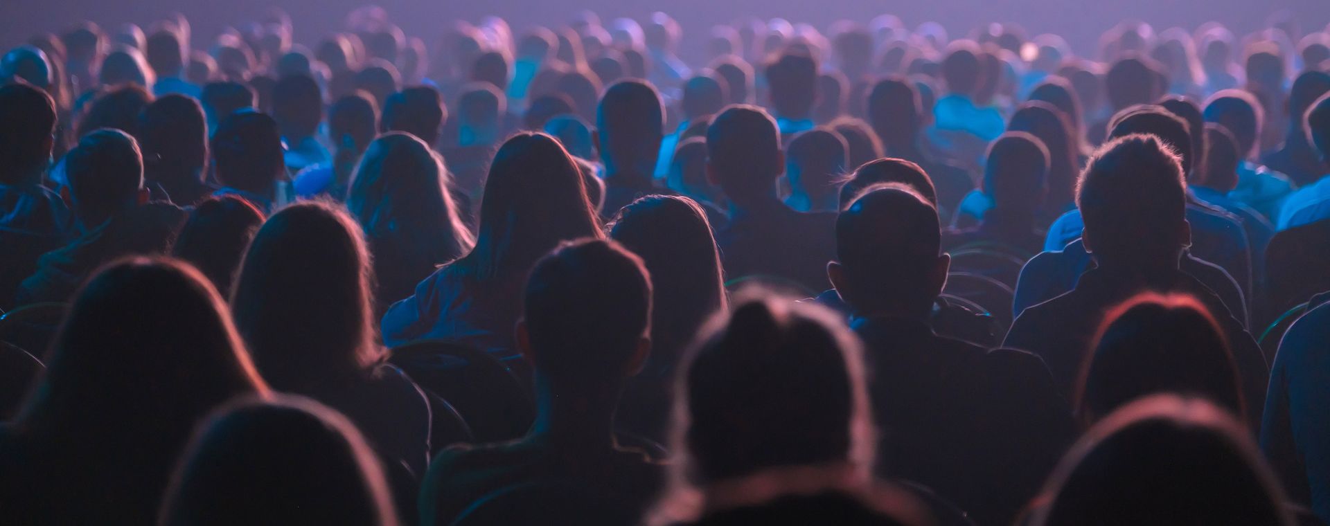 Audience at a concert, silhouettes against stage lights.