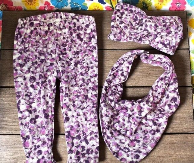 A pair of purple pants a headband and a bib on a table