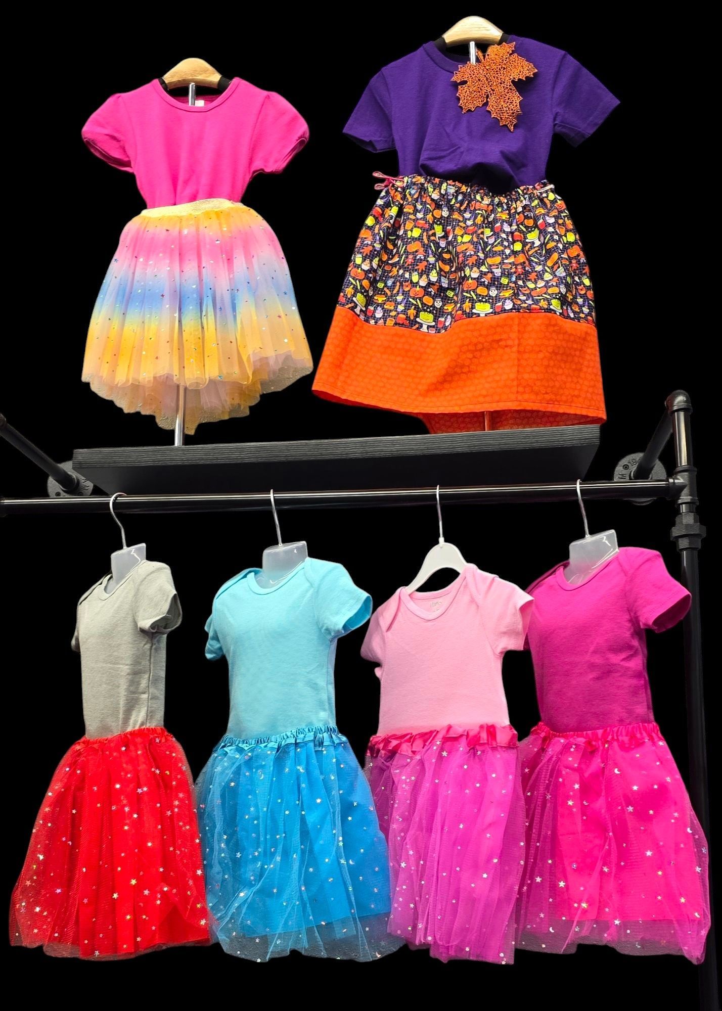 A bunch of children 's dresses are hanging on a rack