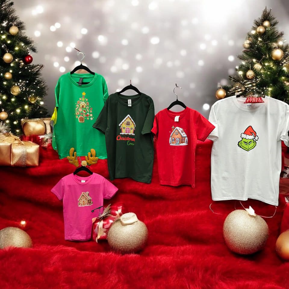 A group of christmas shirts are displayed in front of a christmas tree