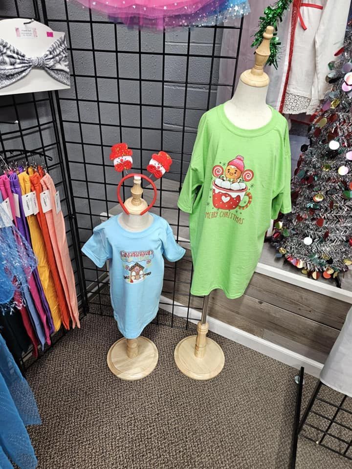 Two mannequins wearing matching shirts are sitting next to each other in front of a christmas tree.