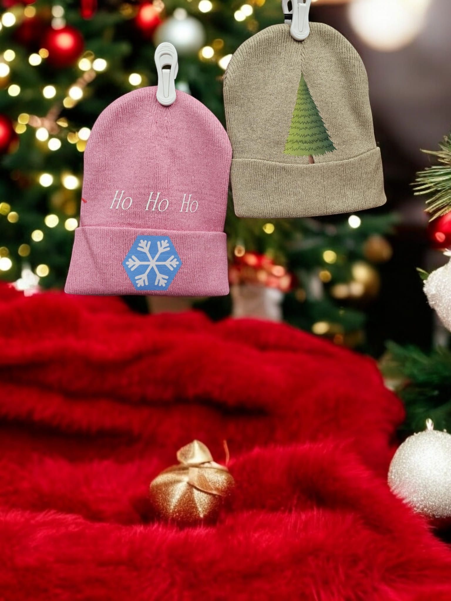 Two christmas hats are hanging on a red blanket in front of a christmas tree.