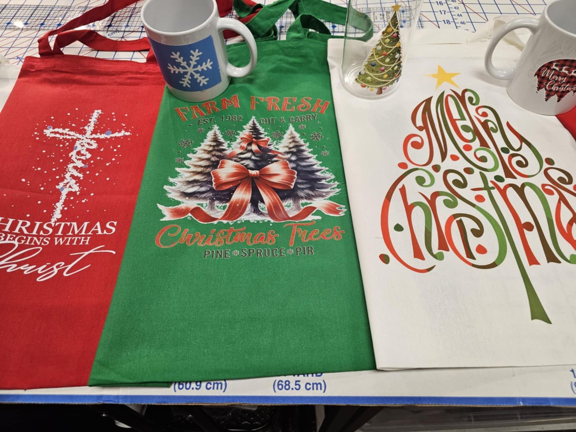 Three christmas towels and mugs are on a table