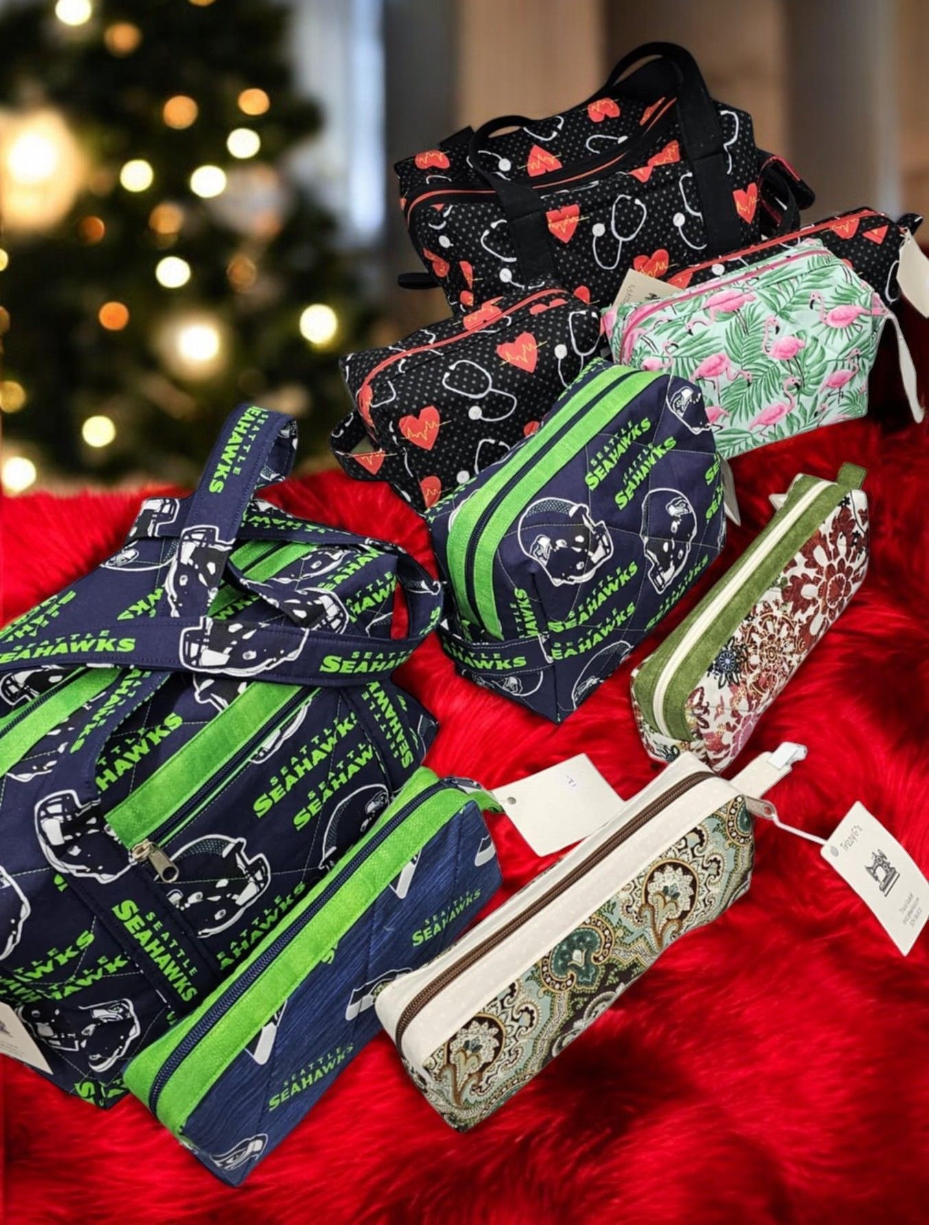 A bunch of pencil cases are sitting on a red blanket in front of a christmas tree.