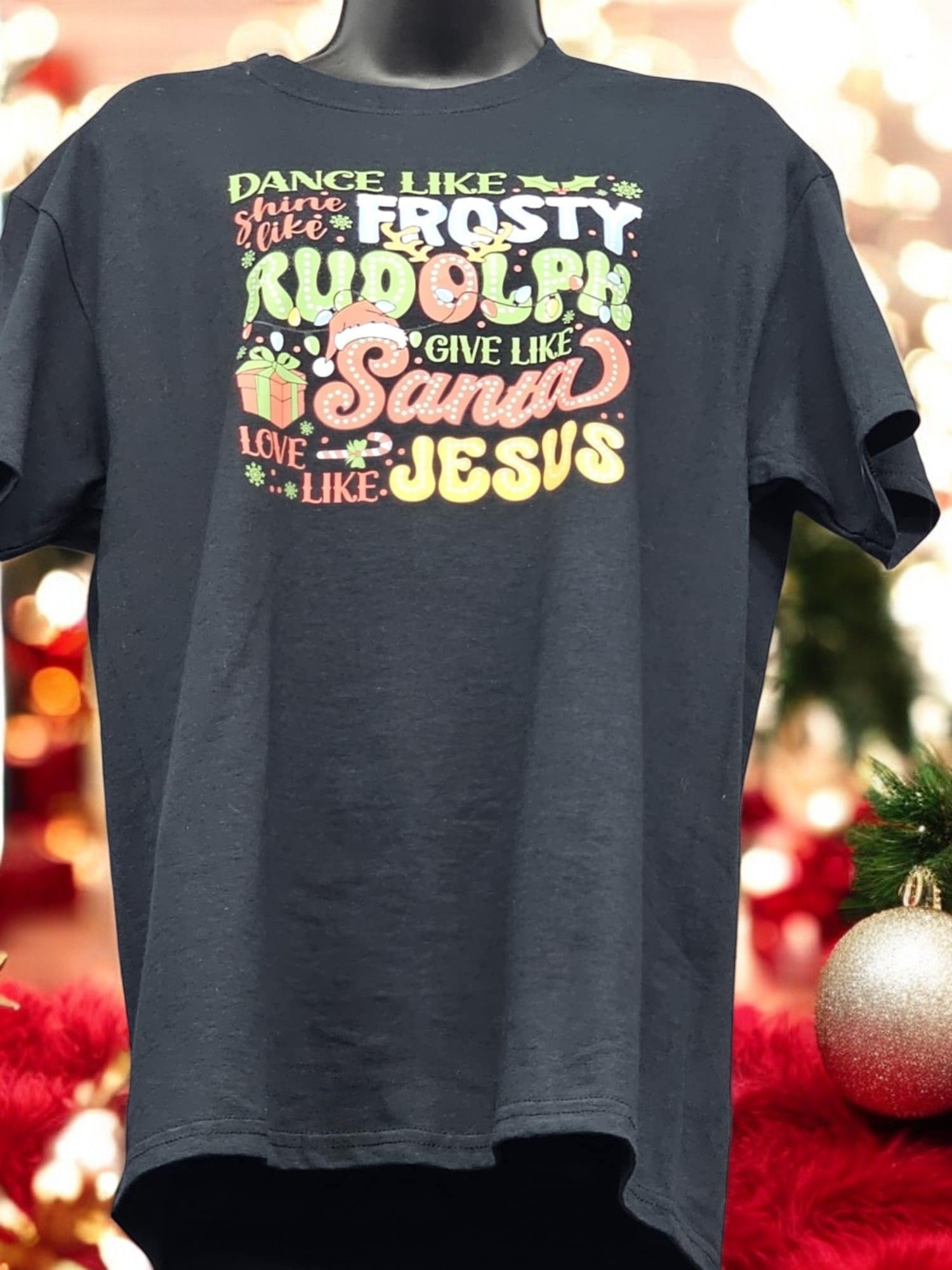 A t-shirt that says dance like frosty rudolph give like santa love like jesus