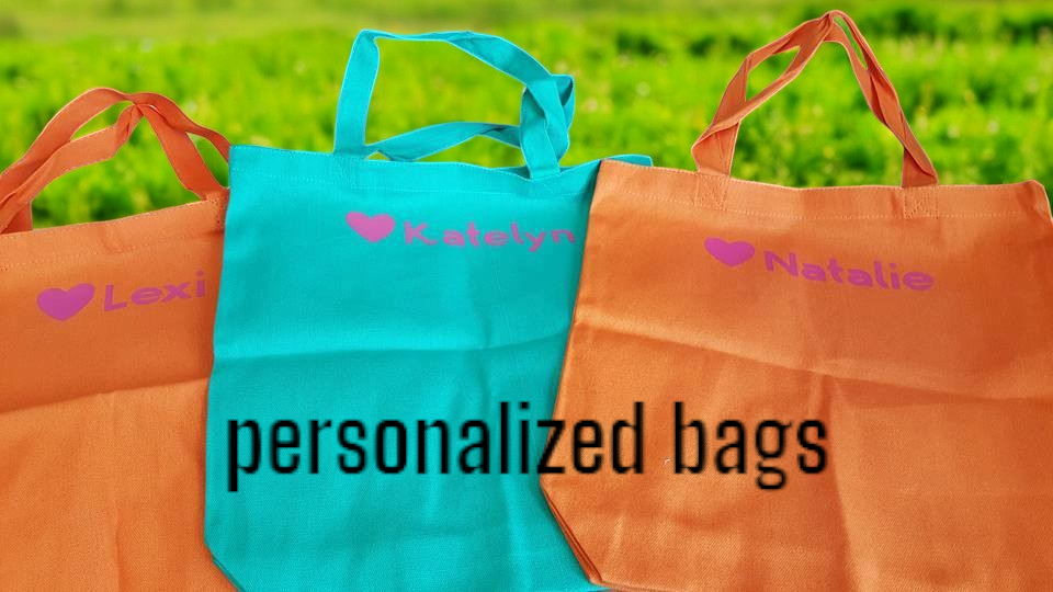 Three personalized bags are sitting on top of each other in a field.