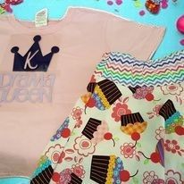A pink shirt with a crown on it and a skirt with cupcakes on it.