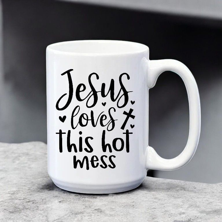 A white coffee mug that says jesus loves this hot mess