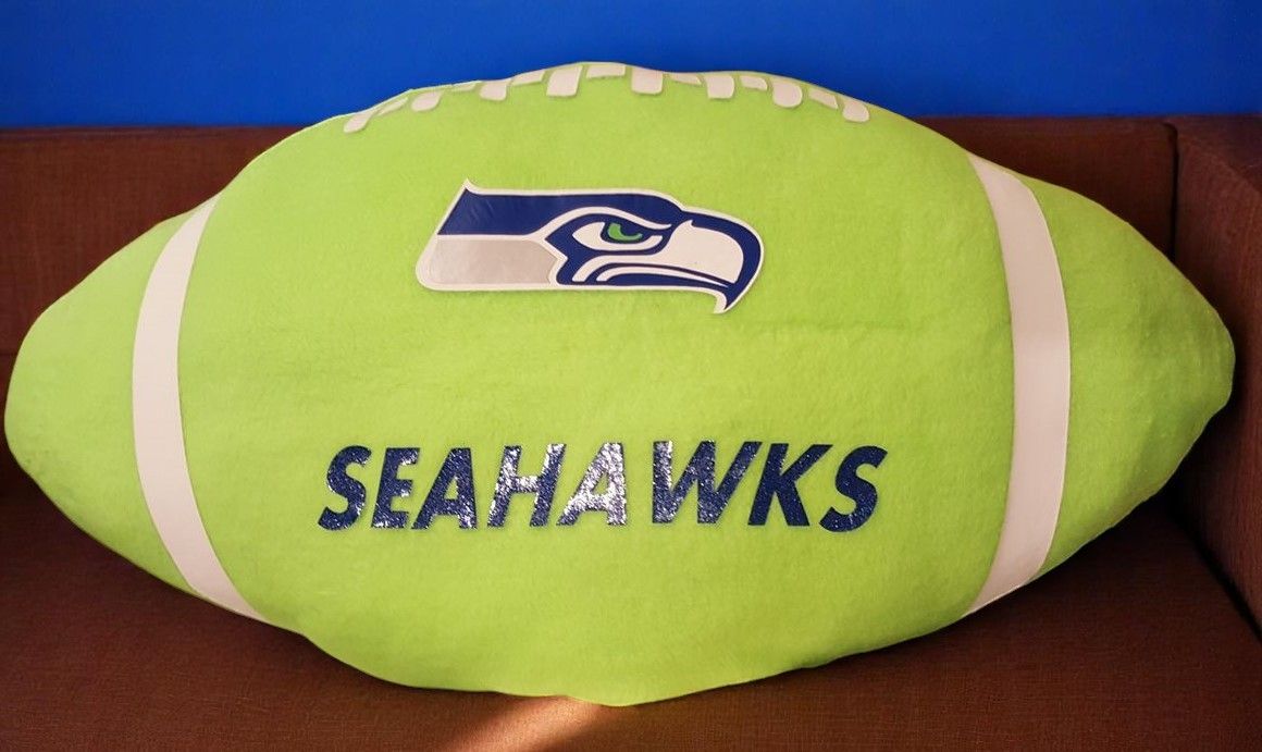 A seahawks football pillow is sitting on a brown surface
