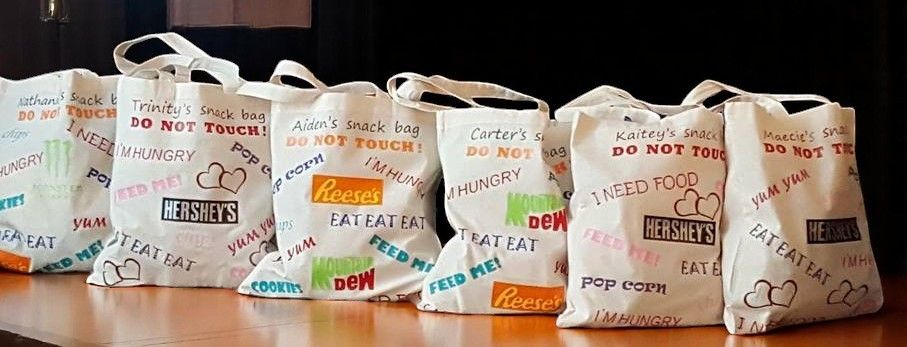 A bunch of bags are lined up on a table and one of them says do not forget