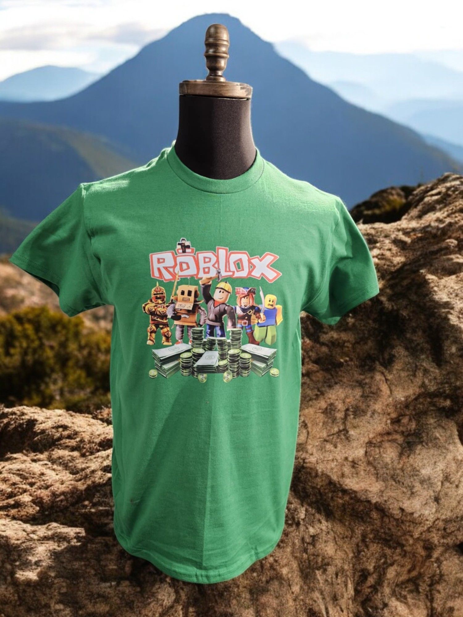 A green roblox t-shirt is on a mannequin in front of a mountain.