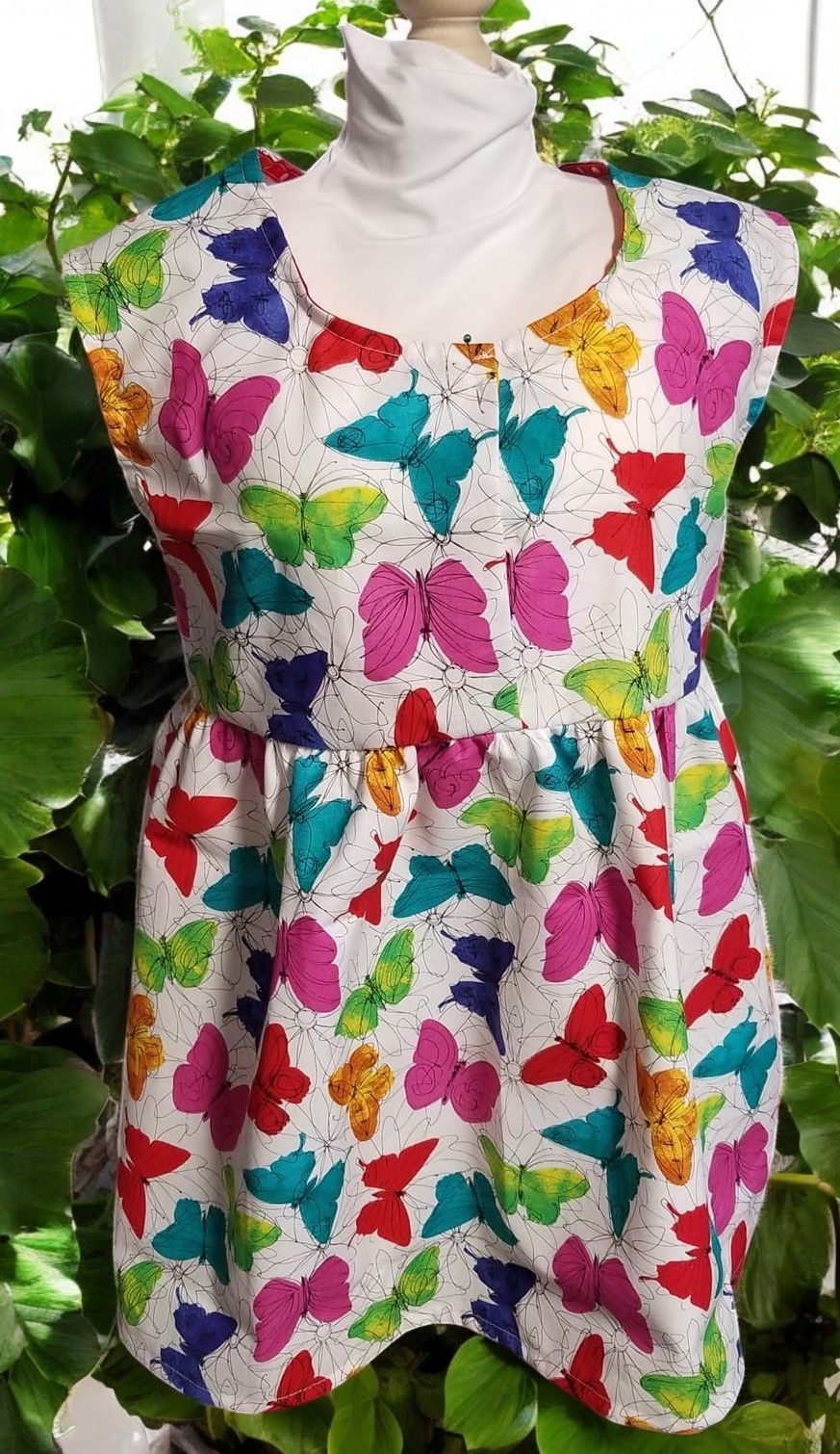 A white dress with colorful butterflies on it is on a mannequin.