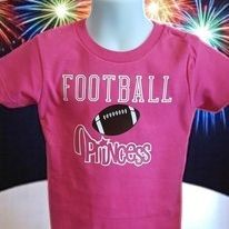 A pink t-shirt with a football on it is on a mannequin.