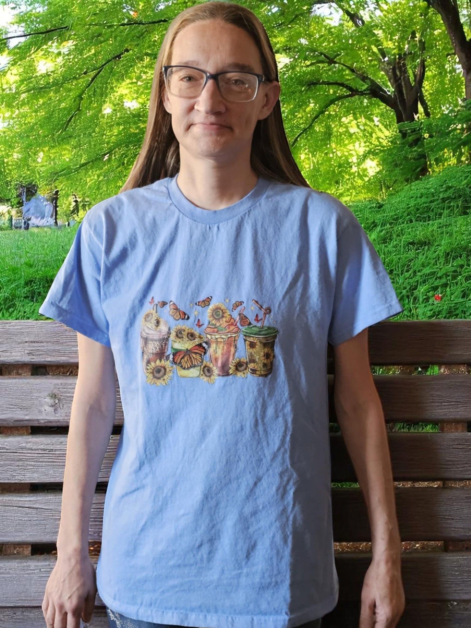 A woman wearing glasses and a light blue t-shirt is standing on a wooden bench.
