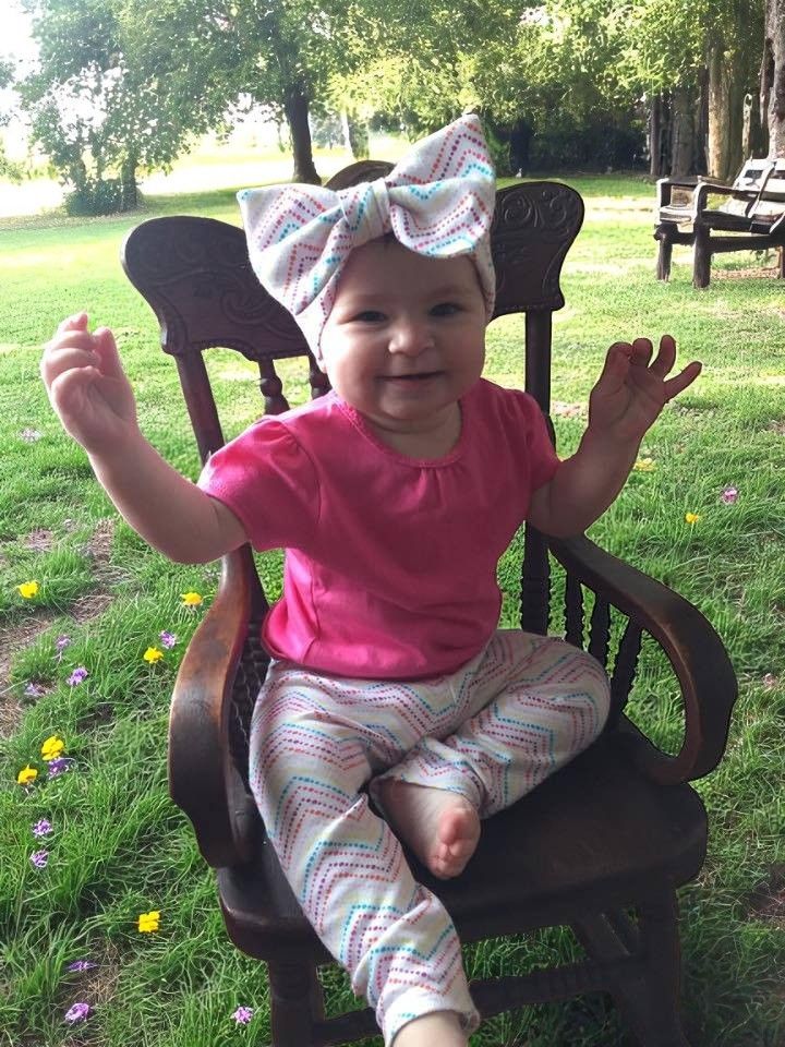 A little girl is sitting in a rocking chair in the grass.