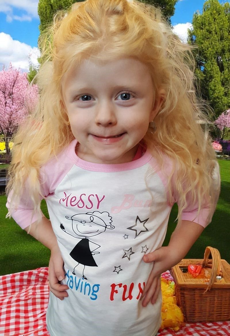 A little girl wearing a shirt that says messy having fun