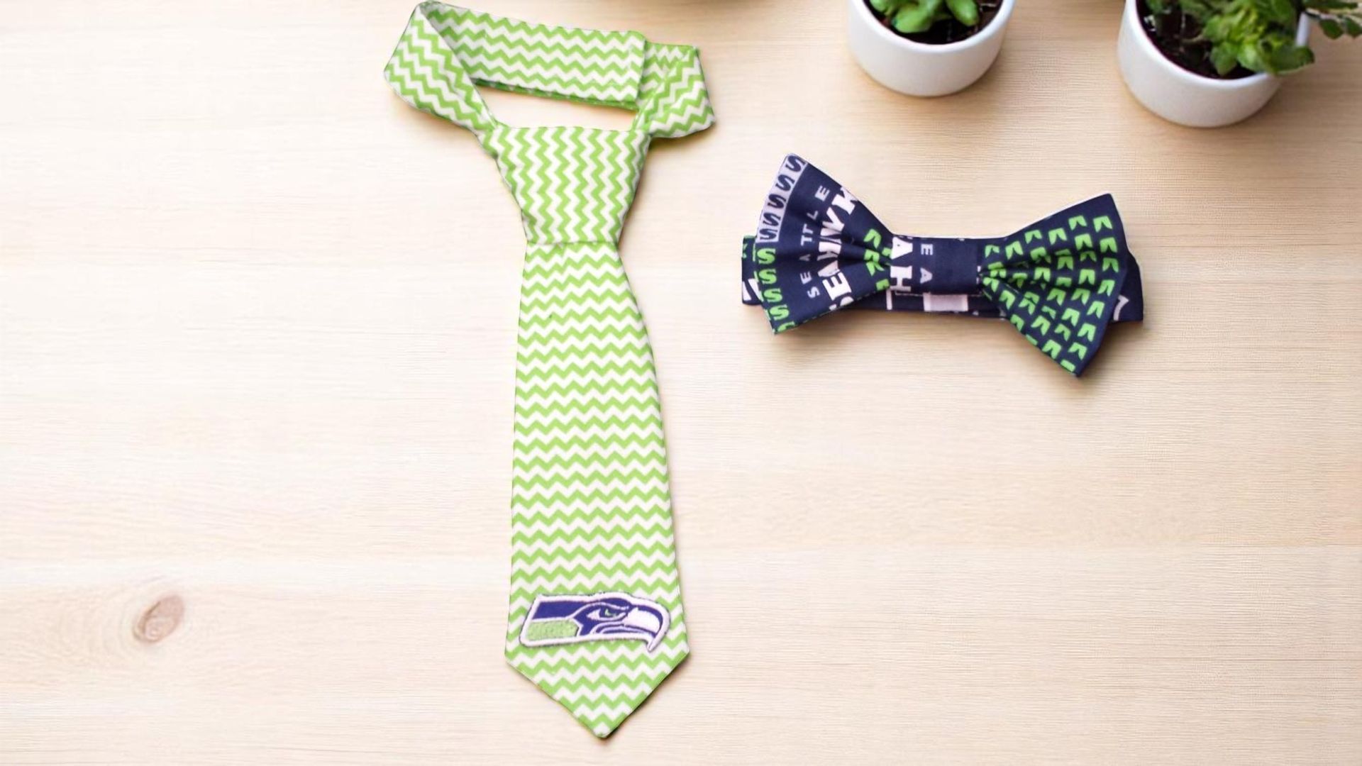A green tie and a blue bow tie are on a wooden table.