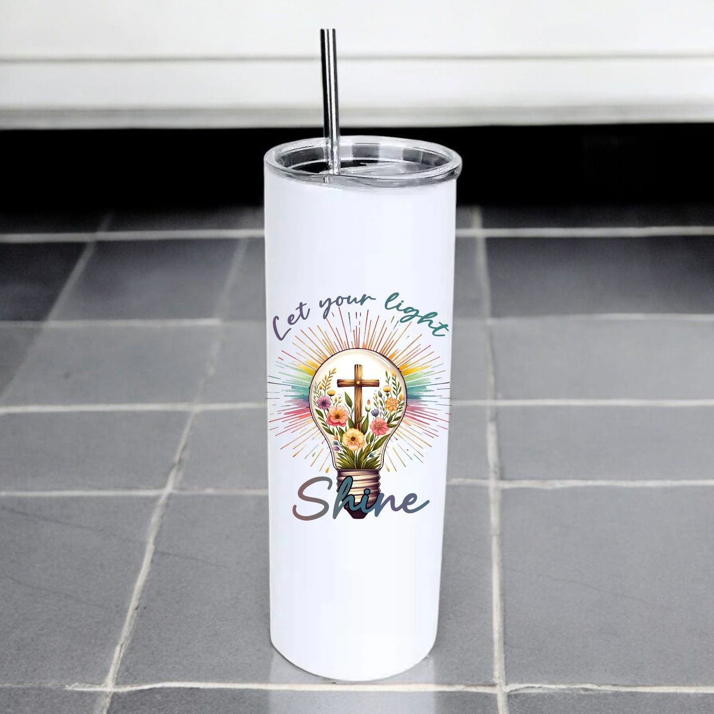 A stainless steel tumbler with a straw and a light bulb with a cross on it.