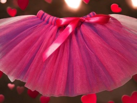 A pink and purple tutu with a red bow