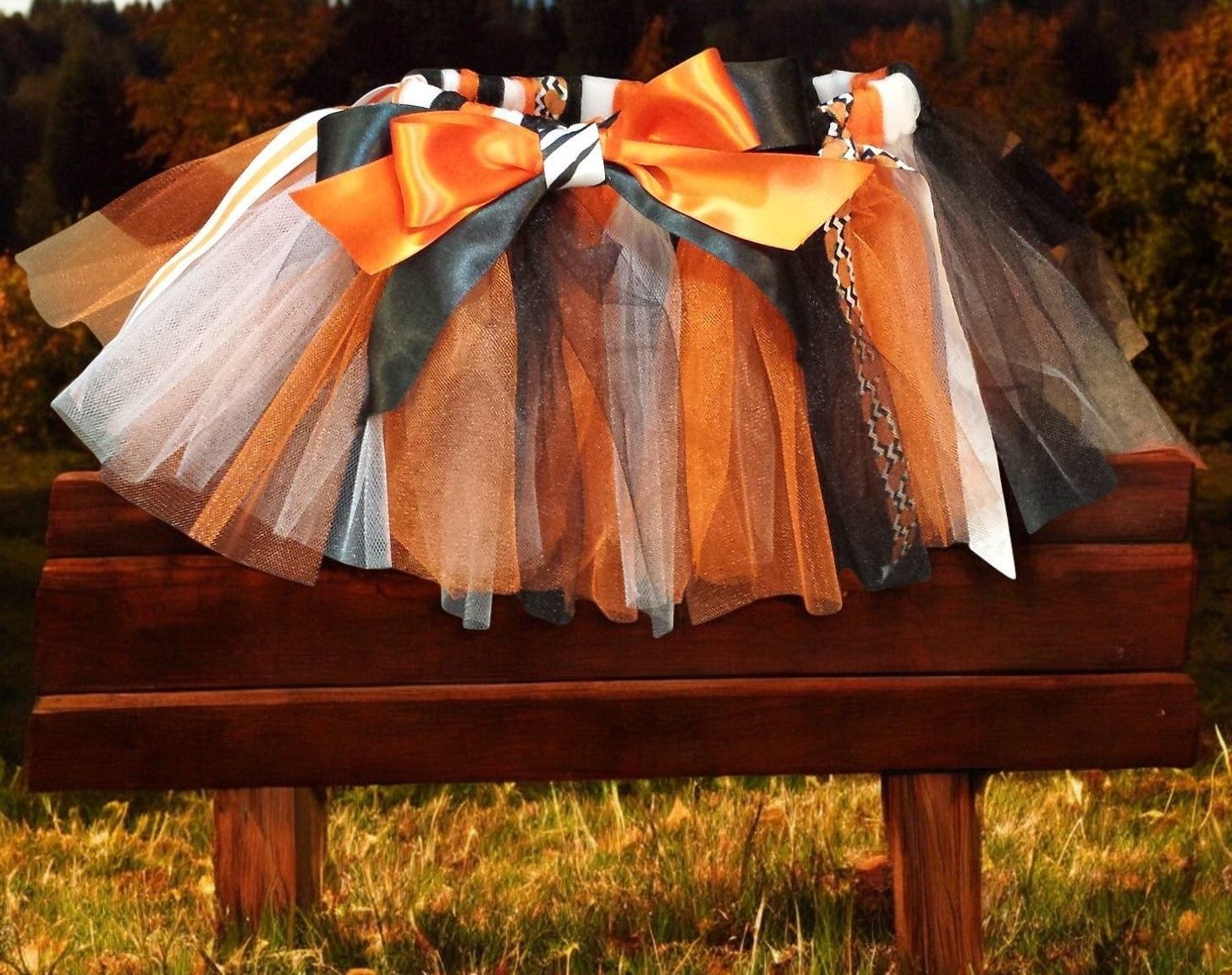 A tutu is sitting on a wooden bench in the grass