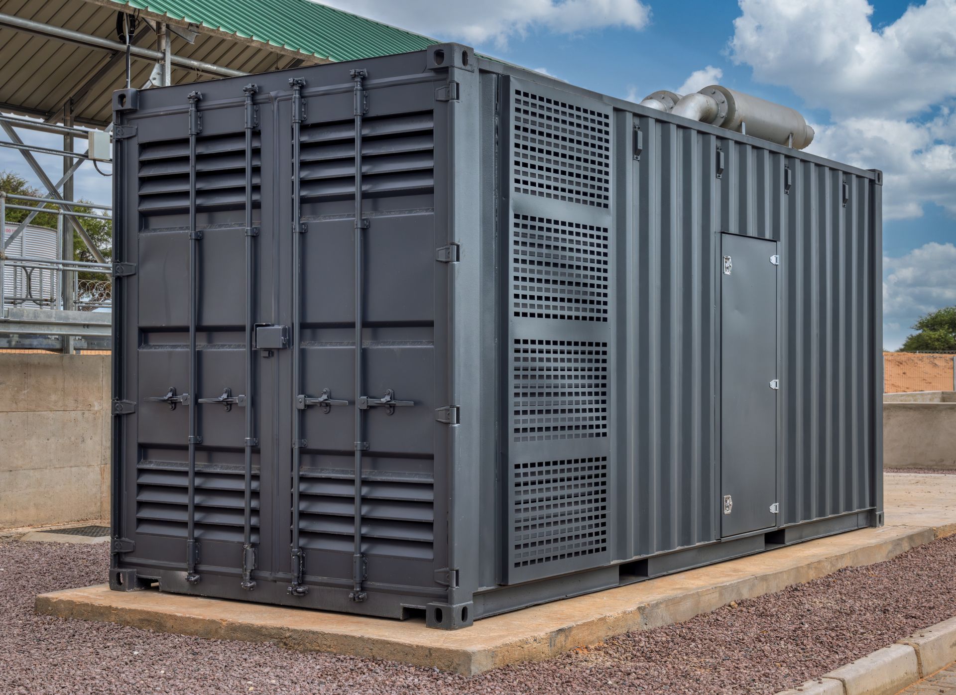A row of white shipping containers modified into outdoor storage units with rolling doors, set on a gravel lot.