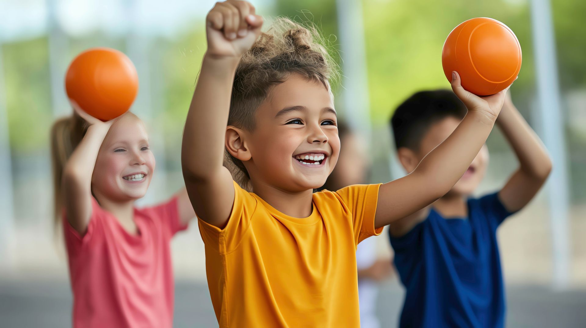 Eine Gruppe Kinder spielt in einer Turnhalle mit Bällen.