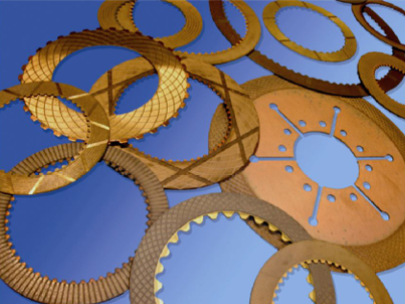 Una colección de varias placas de fricción de color dorado sobre un fondo azul, probablemente para un dispositivo mecánico.