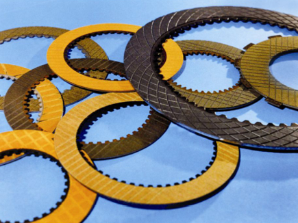 Placas de fricción circulares con superficies texturizadas en amarillo y gris oscuro sobre una superficie azul.